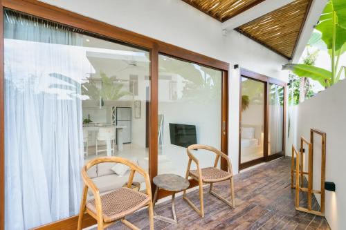 two chairs and a table on a balcony with a living room at Pagi Villas by Betterplace in Canggu
