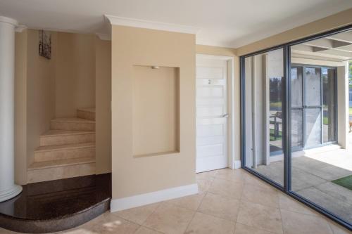 un pasillo de una casa con puertas de cristal y escaleras en Ocean View Executive Apartment 1, en Busselton