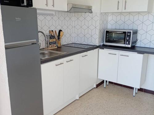 - une cuisine blanche avec un four micro-ondes et un évier dans l'établissement F1 cosy avec loggia et 4 couchages à Balaruc-les-Bains, animaux admis - FR-1-680-40, à Balaruc-les-Bains