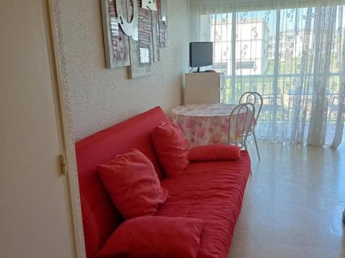 - un canapé rouge dans le salon avec une table dans l'établissement F1 cosy avec loggia et 4 couchages à Balaruc-les-Bains, animaux admis - FR-1-680-40, à Balaruc-les-Bains
