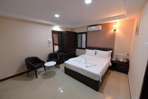 a bedroom with a bed and a table and a chair at Coastal Grand Hotel Sampath in Tiruchchirāppalli