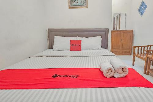 a bed with a red blanket on top of it at RedDoorz near Alun Alun Cianjur in Cianjur