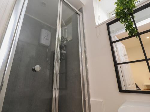 a shower with a glass door next to a window at Basement Flat 43 in Keighley