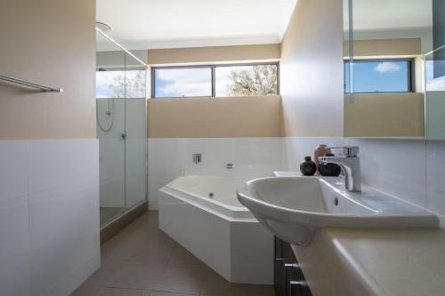 La salle de bains est pourvue d'un lavabo, d'une baignoire et d'une douche. dans l'établissement Ocean View Executive Apartment 4, à Geographe
