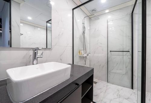 a white bathroom with a sink and a shower at Reina Hotel in Busan