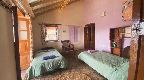 ein Schlafzimmer mit 2 Betten und einem Stuhl darin in der Unterkunft Adara Farmstay in Pauri