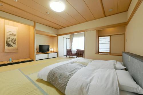 a bedroom with a large bed and a television at Hanasuishou in Fuefuki