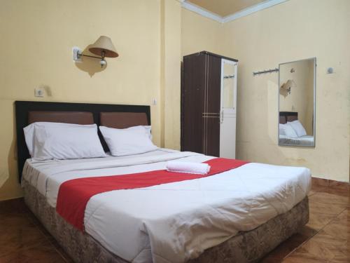 a bedroom with a large bed with a red blanket at RedDoorz Syariah At Hotel Matahari 1 Jambi in Jambi