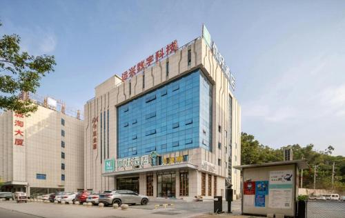 a large building with cars parked in a parking lot at Nihao Hotel Quanzhou Donghu Street in Quanzhou