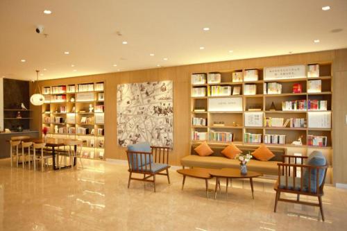 a library with a couch and a table and chairs at Hanting Hotel Tangshan Yutian Yahong Bridge in Fengrun