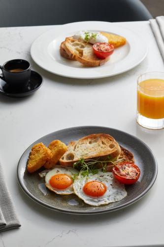 a plate of eggs and toast on a table with orange juice at Oakwood Premier Melbourne in Melbourne