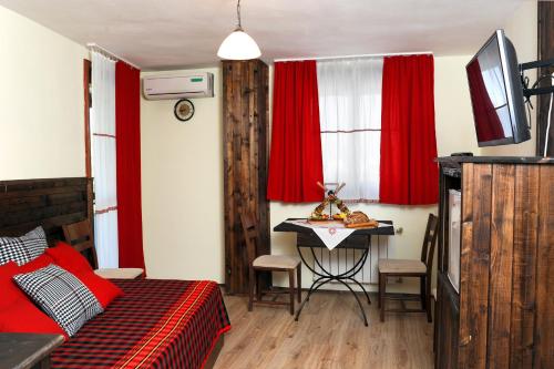 a bedroom with a bed and a table and red curtains at Hotel Simona Complex in Sofia