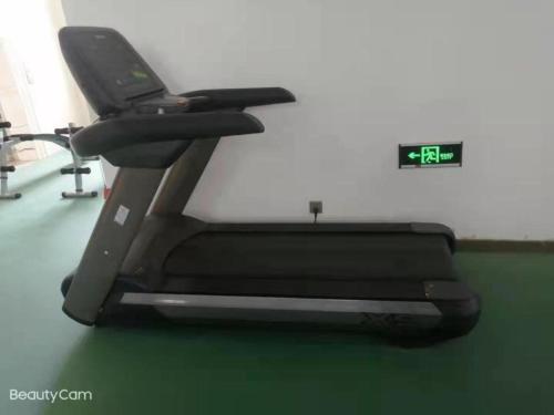 - un tapis de course dans une salle de sport avec horloge dans l'établissement Madison Lanzhou Lanshi Zhongchuan Airport, à Hejialiang