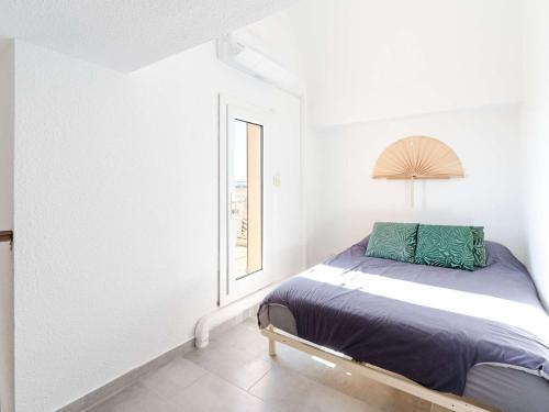 un lit dans une chambre blanche avec une fenêtre dans l'établissement Duplex T2 climatisé, terrasse, proche port - 4 pers. - FR-1-409-254, à Gruissan