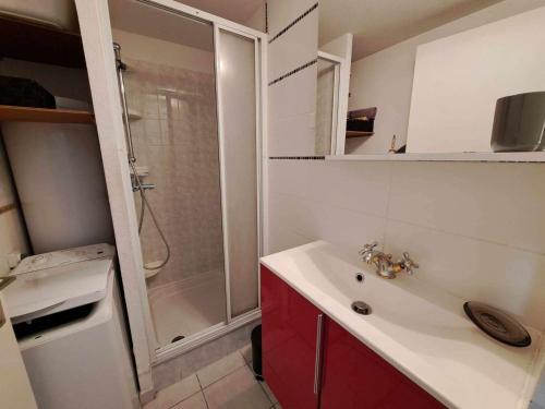 La salle de bains est pourvue d'une douche et d'un lavabo blanc. dans l'établissement Maison mitoyenne climatisée avec piscine, grande terrasse, proche plage à Marseillan - FR-1-326-809, à Marseillan