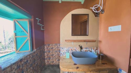 La salle de bains est pourvue d'un lavabo bleu et d'un miroir. dans l'établissement Adara Farmstay, à Pauri
