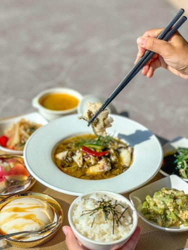 a table with a plate of food with people holding chopsticks at 愛琴海岸精品民宿 in Fangliao