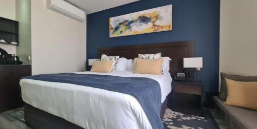 1 dormitorio con 1 cama grande y pared azul en Grand Aria Hotel, en Gaborone