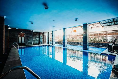 uma grande piscina com água azul num edifício em The Priangan Hotel @ Sudirman em Nagrak