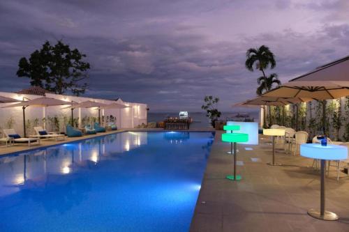 una piscina por la noche con mesas y sombrillas en 1521 Hotel Mactan en Isla de Mactán