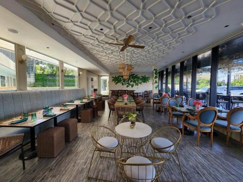1521 Hotel Mactan في ماكتان: مطعم بطاولات وكراسي ونوافذ