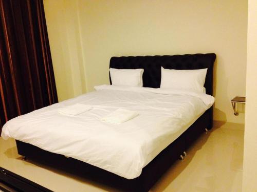 uma cama grande com lençóis brancos e almofadas brancas em นิวธาราเพลส หล่มสัก โรงแรม em Ban Nam Phung