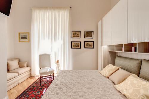 een witte slaapkamer met een bed en een bank bij Casa Claudia Giulio Cesare in Rome