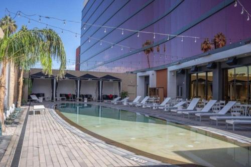 uma piscina com cadeiras brancas e um edifício em Ahern Hotel and Event Center em Las Vegas