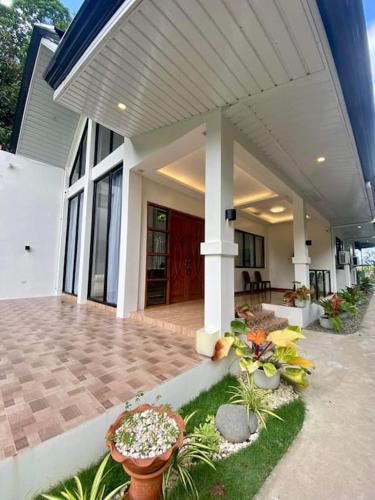a house with a porch with potted plants in front of it at Casa Darcera in Dipolog