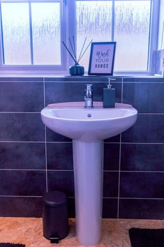 a white sink in a bathroom with a sign on it at City Vibes Getaway in Leeds