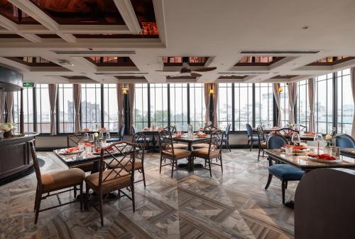 a dining room with tables and chairs and windows at GRAND HOTEL du LAC Hanoi in Hanoi