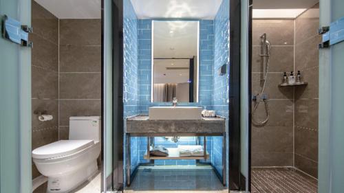 a bathroom with a sink and a toilet and a shower at Echarm Hotel Wuzhou Wangcheng Plaza Longmumiao Sanzongfu in Wuzhou