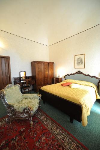 a bedroom with a bed and a chair at Hotel Villa Kinzica in Pisa