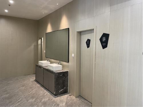 łazienka z 2 umywalkami i telewizorem na ścianie w obiekcie Echarm Hotel Wuhu Wanzhi East Lake Yingbin Avenue w mieście Liangzhongchang