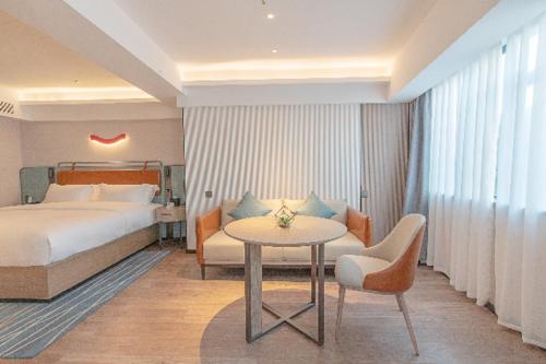 a hotel room with a bed and a table and chairs at Echarm Hotel Panzhihua Hubin Road in Panzhihua