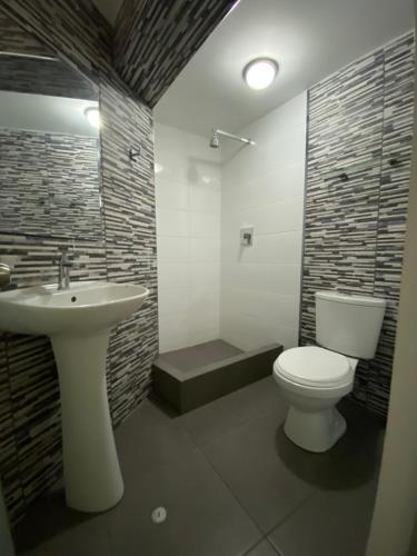 een badkamer met een wit toilet en een wastafel bij Wayra Hotel in Huaraz