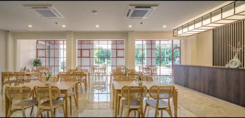 uma grande sala com mesas, cadeiras e janelas em Kio Hotel Korat em Ban Hua La Loeng