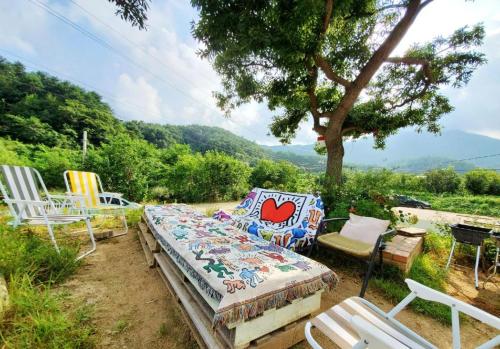 łóżko i krzesła siedzące pod drzewem w obiekcie Seorak Jaeins Garden w mieście Yangyang