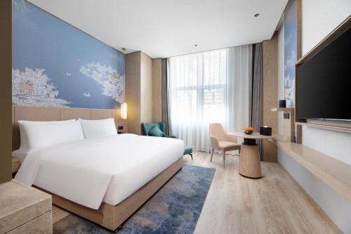 a hotel room with a large white bed and a tv at Grand Madison Hotel Wuhan Optical Valley Canglongdao in Liufangling