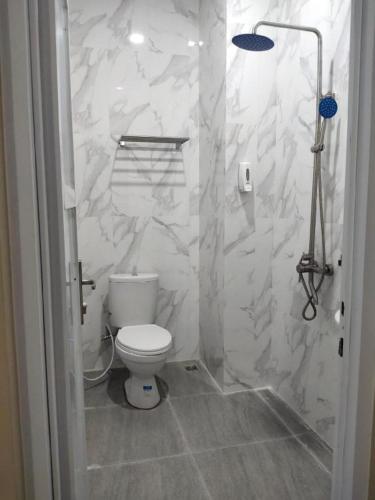 a white bathroom with a toilet and a shower at Arro hotel bukittinggi (syariah) in Gadut