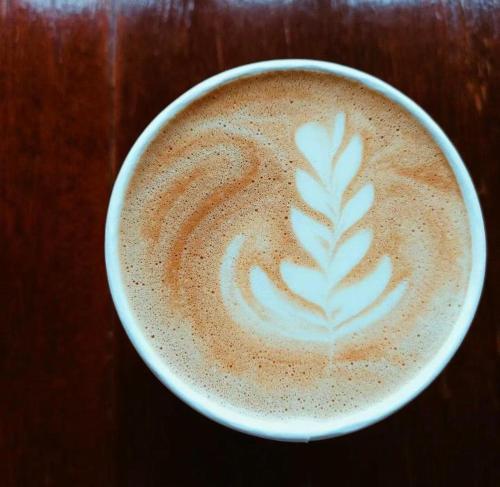 uma chávena de cappuccino com uma folha pintada. em Mango Valley Hotel 5 em Olongapo