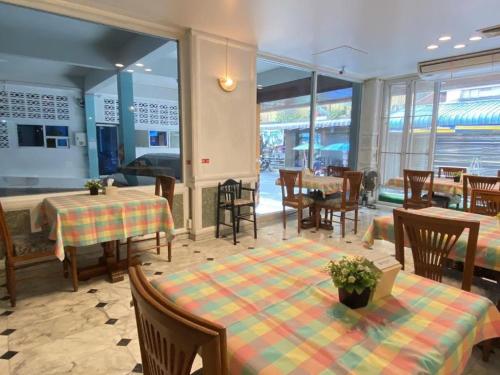 uma sala de jantar com mesas, cadeiras e janelas em โรงแรมไทยโฮเต็ล em Nakhon Si Thammarat