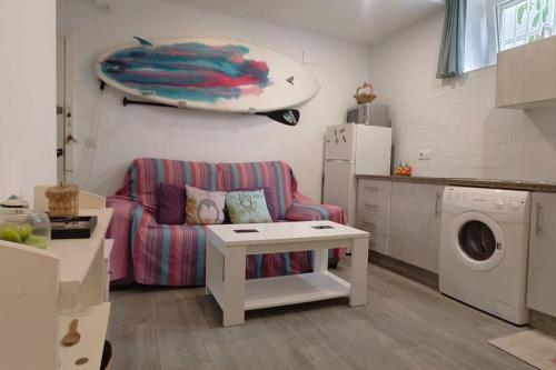 een woonkamer met een bank en een surfplank aan de muur bij Apartamento a pie de playa. in Chiclana de la Frontera