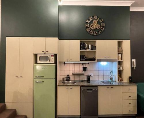 cocina con nevera verde y armarios blancos en Neutral bay studio, en Sídney