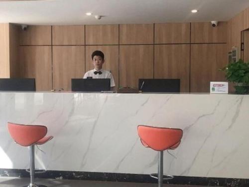 a man sitting at a table with a laptop at Green Tree Inn Liaoning Panjin Wanda Plaza Tianjia in Panjin
