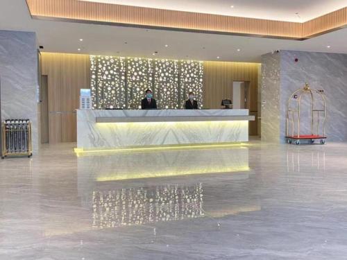 a lobby with a reception counter and people in a building at Green Tree Inn Shache County Lvcheng Times Plaza in Shache