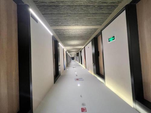 um longo corredor com paredes brancas e um tecto em Green Tree Inn Aksu Municipal Government em Aksu