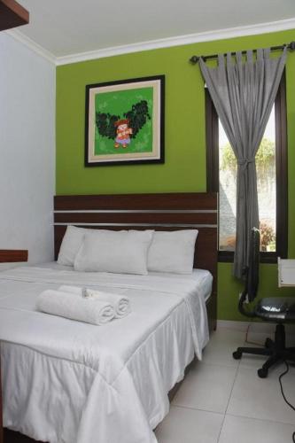 ein Schlafzimmer mit einem Bett mit einer grünen Wand in der Unterkunft De Jati House in Cibening Empat