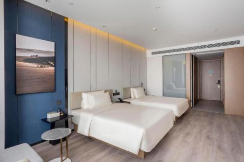 1 dormitorio con 2 camas y pared azul en Atour Hotel Tianjin Shengtaicheng Maritime Museum, en Binhai