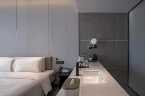 a bathroom with a sink next to a bed at Atour Hotel Tianjin Shengtaicheng Maritime Museum in Binhai